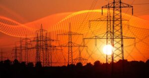 data grid over silhouette of several high-voltage power lines and electricity pylons against a glowing orange and red sunset sky
