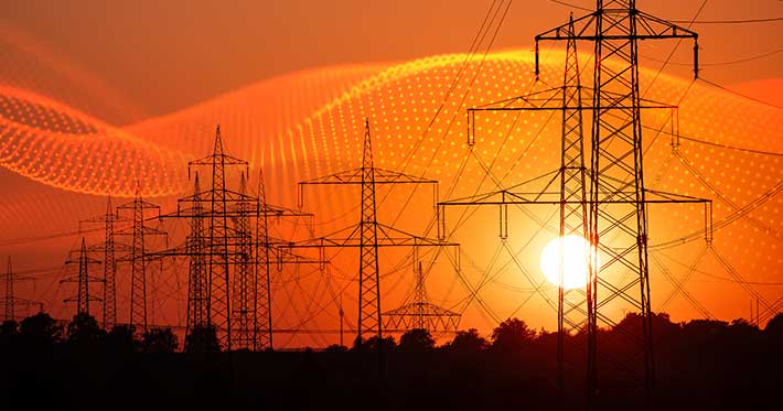 data grid over silhouette of several high-voltage power lines and electricity pylons against a glowing orange and red sunset sky