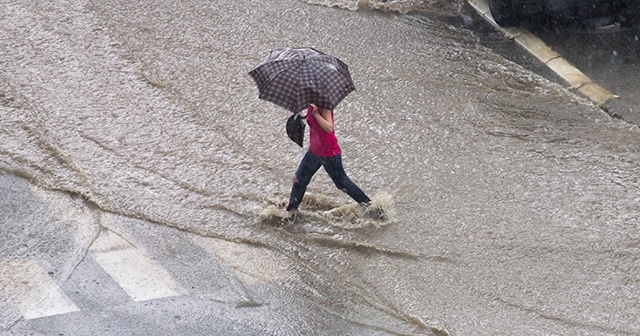 Woman walking through flooded street in the rain