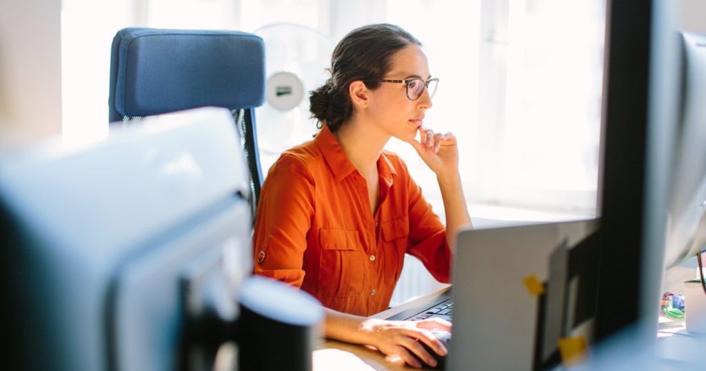 woman in orange shirt at computer