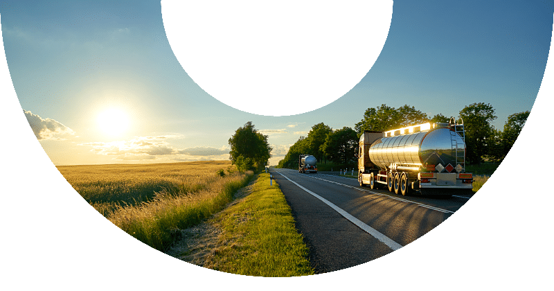 two fuel trucks driving down rural interstate road at sunset