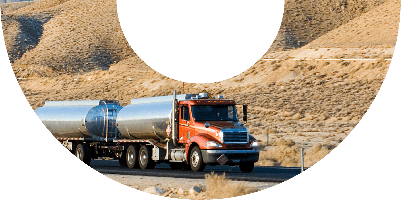 amber truck with two tanks driving down desert road