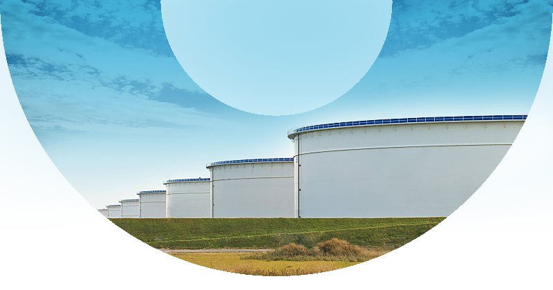 row of white storage tanks in distance with blue sky