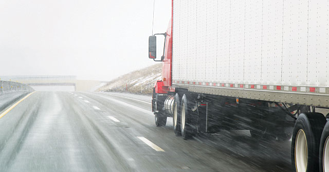 red semi truck on wet road driving up a hill