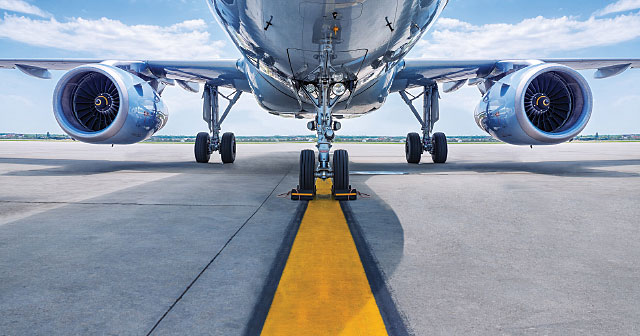 airplane chrome underside on runway with yellow pavement stripe