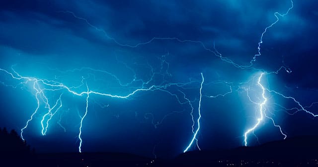 vivid night blue sky lightning over city lights