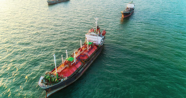 aerial of red gas tanker on green ocean