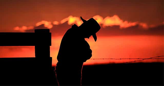farmer silhouette with head low at sunset
