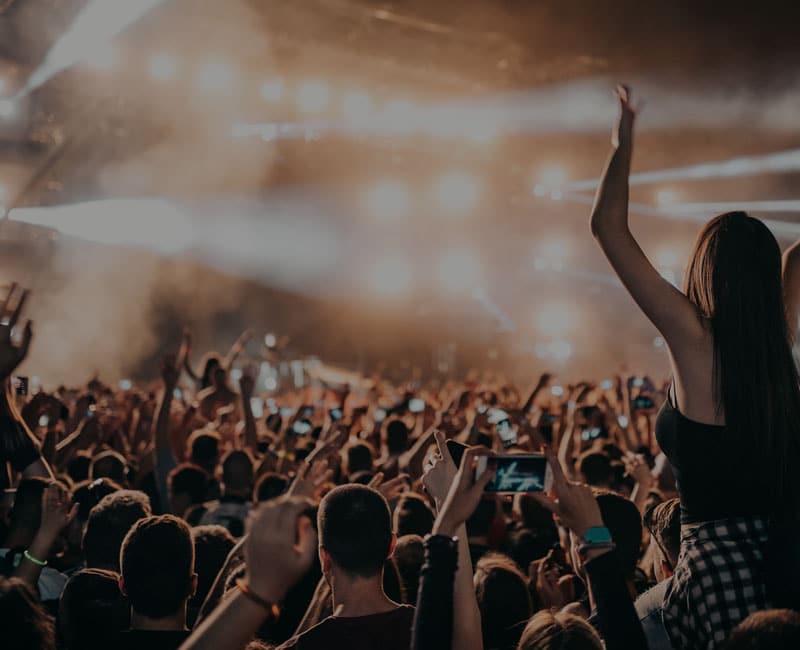 lights shining over concert goers raising hands