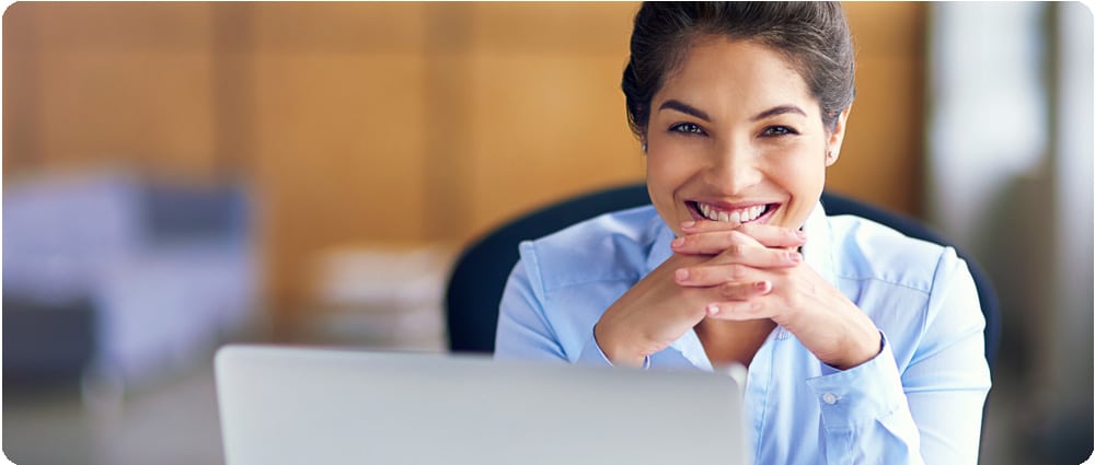 Business woman smiling behind laptop