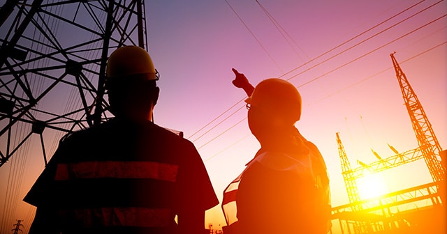 Electrical workers looking at pylon