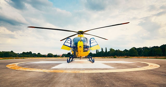 yellow helicopter on pad cloudy sky background