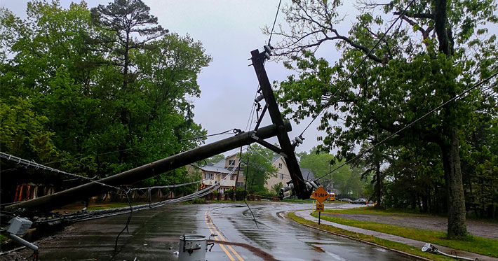 Downloaded transformer on a pole and a tree laying across power lines over a road
