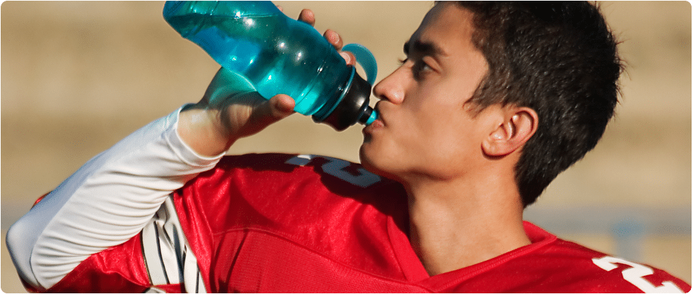 High school football player drinking from water bottle