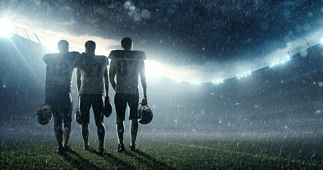 Football players standing on the field in the rain