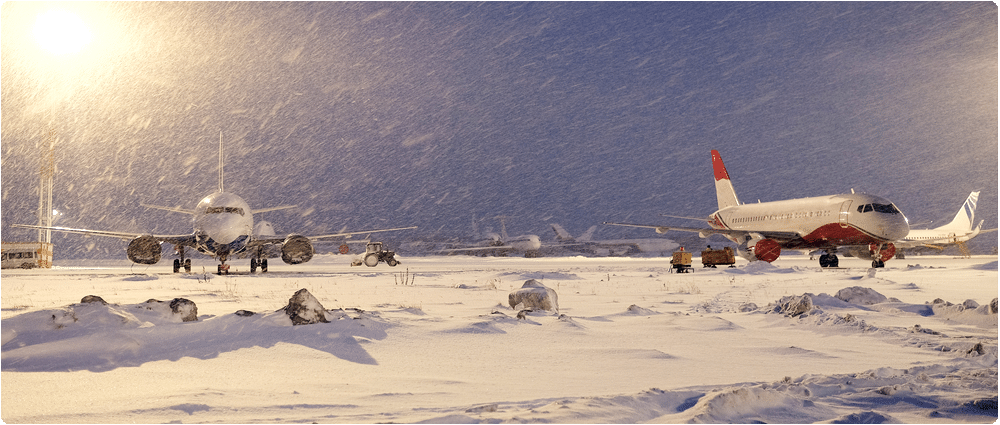 Two airplanes sitting in snowstorm