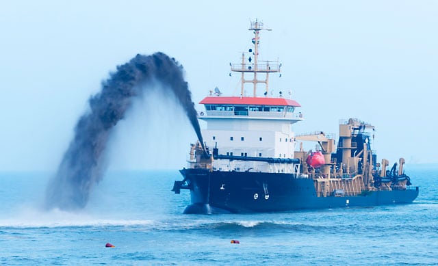 Spout of a dredger at work to reclaim beach erosion.