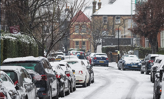 snow covering parked cars on city street