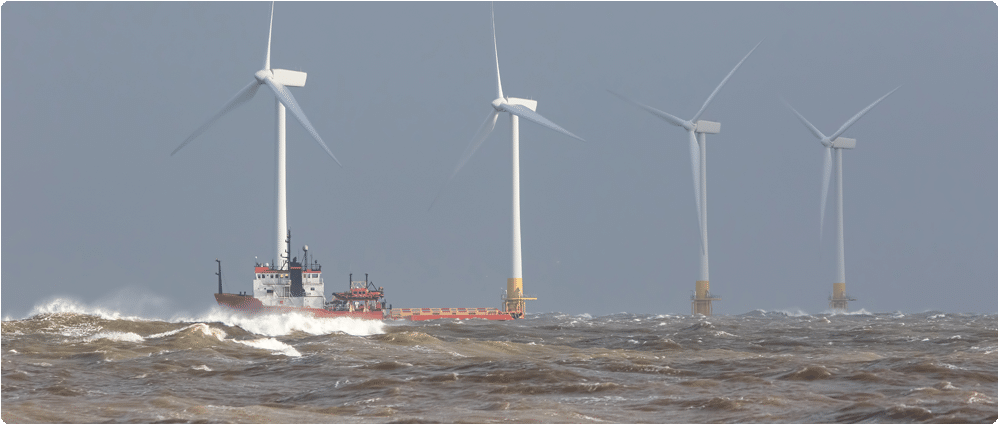 Ship in rough sea near offshore wind farm