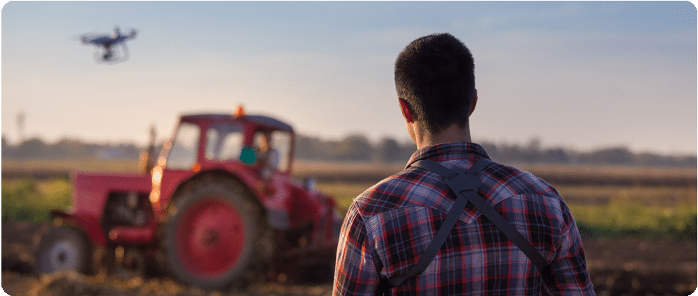 Farmer controlling drone over tractor