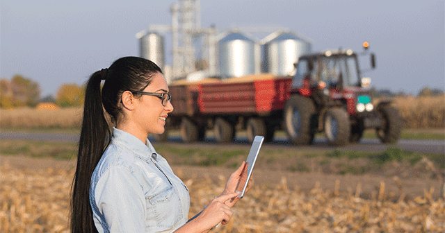Blog header Agronomist with tablet in front of tractor and grain elevator