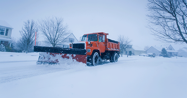 Snowplow driving down residential street