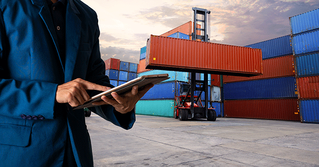 Worker on tablet in front of cargo