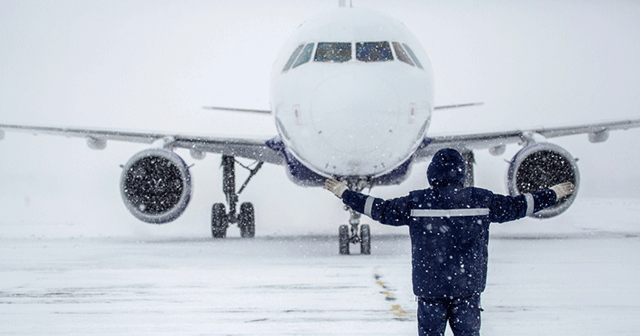 Airplane in winter with ground crewman