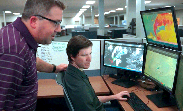 2 meteorologists monitoring multiple computer screens help inform DTN weather solutions