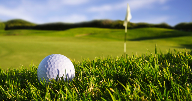 Closeup of golfball in the rough with the flag in the background