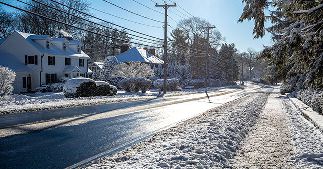 A winding suburban street just after a fresh snowfall.