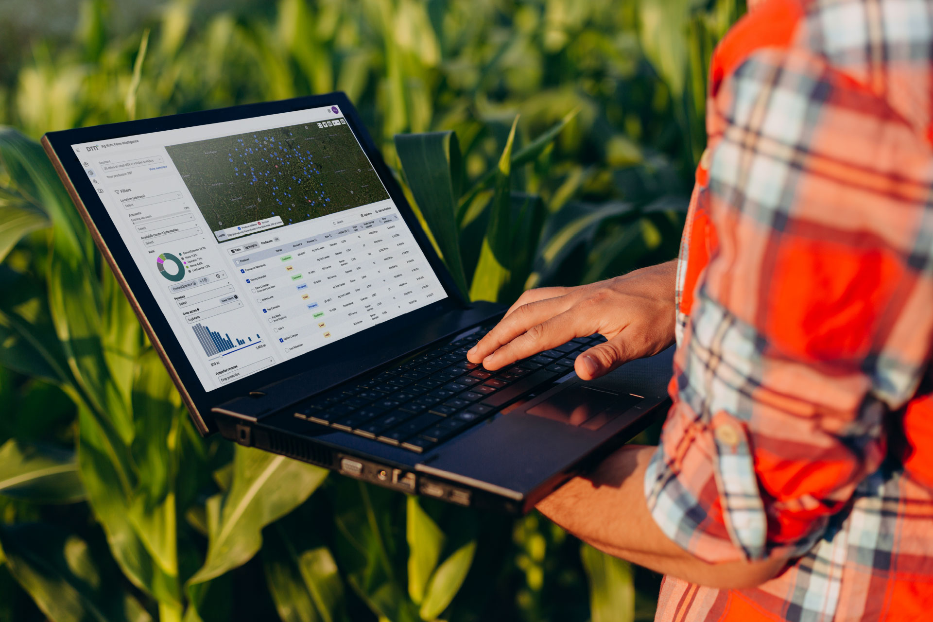 DTN farm intelligence farmer with hand on laptop in corn field