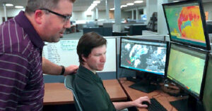 2 DTN meteorologists monitoring multiple computer screens help inform DTN weather solutions