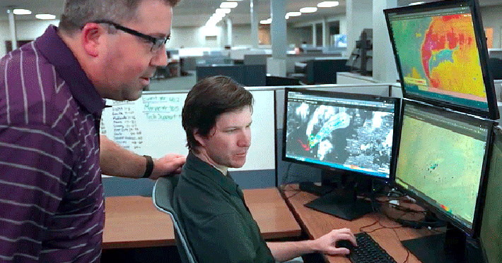 2 DTN meteorologists monitoring multiple computer screens help inform DTN weather solutions
